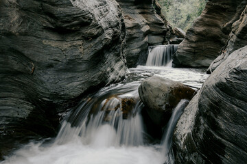 Close-up shot of a waterfall cascading down a rock in slow motion, laterite palace, Pua Nan.