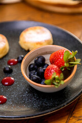 cheesecakes with berries on a plate garnished with jam. healthy breakfast.