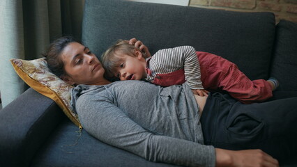Obraz premium Exhausted mother lying on sofa with child