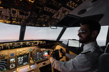 cheerful pilot in sunglasses using yoke while piloting in evening. © LIGHTFIELD STUDIOS