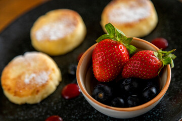 cheesecakes with berries on a plate garnished with jam. healthy breakfast.