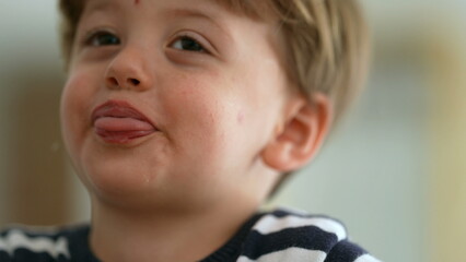 Cute little boy spitting to camera sticking tongue out being playful