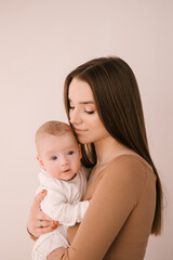 Loving smiling young mother with her newborn daughter in a bright room