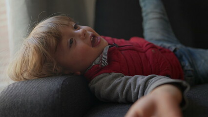 Cute child boy lying on sofa looking at camera © Marco