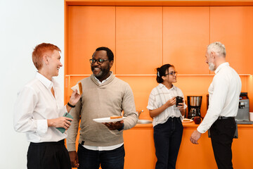 Multiracial colleagues talking and having sandwiches in office
