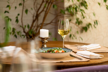 Naklejka na ściany i meble fresh salad served with a glass of wine. served table