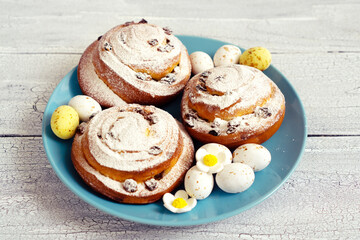 Delicious fresh pastries with icing sugar on a blue plate with chocolate sweet eggs for Easter gift