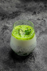 Healthy breakfast chia pudding with kiwi in glass jars on dark table. Clean eating, dieting, vegan food concept. vertical image