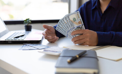 Wealthy businessman holding cash and counting money on his desk at home.