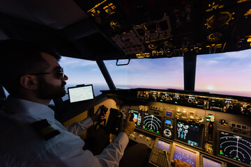 bearded pilot in sunglasses using yoke while piloting in evening.