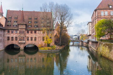 Obraz premium Nuremberg landmark. Medieval hospital museum house over canal. Old town of Nuremberg, Germany. Tranquil autumn landscape in old town. Fall season in historical downtown.