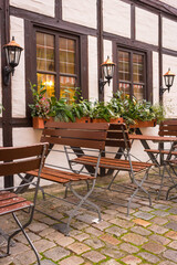 Fototapeta na wymiar Sidewalk cafe decoration. Outdoor cafe in old town in Germany. Flower pot and street lantern on house facade. Half-timbered decorated house in Nuremberg. Medieval architecture.