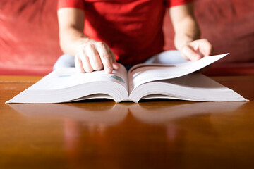 A person in a red shirt consults the solution in a book and finds it, blurred background, selective focus