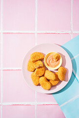 Vegetarian Nuggets with Vegan Dipping Sauce on apink pop art background with space for text,...
