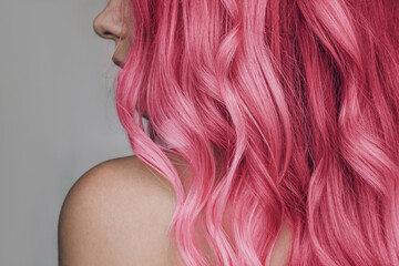 Close-up of the wavy pink hair of a young woman isolated on a gray background. Result of coloring,...