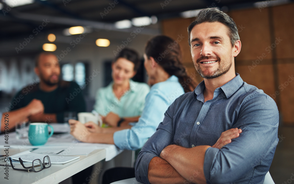 Poster the creative process. portrait of a mature man sitting at a table in an office with colleagues worki