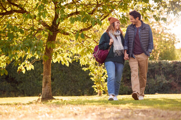 Fototapeta premium Happy Loving Couple Holding Hands Walking In Autumn Park Together