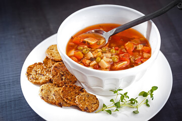 Vegan vegetable soup with raw crackers in a white bowl