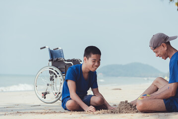Fototapeta premium Young man with disability and parent or volunteer or caregiver relaxing and doing sea beach activities with family at the outdoor vacation in summer, People leisure travel and mental healthy concept.