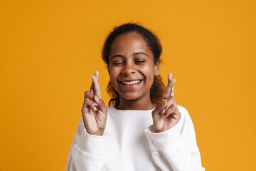 Brunette black girl smiling while holding fingers crossed for good luck