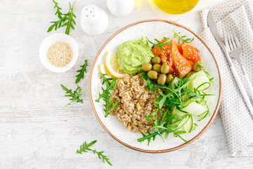 Oatmeal with salted salmon, avocado guacamole and fresh vegetable salad of arugula, cucumbers and olives. Breakfast. Top view