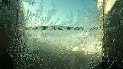 Ice crystals formed on a window pane on a sunny day during winter