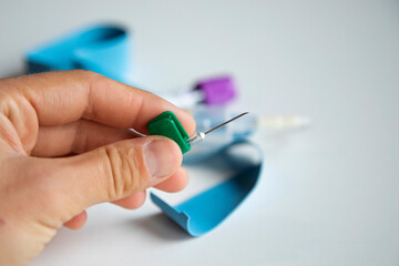 woman's hand holding needle to draw blood