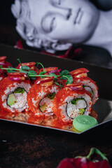 red sushi in a box on the background of an ancient Greek statue