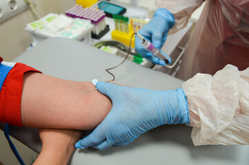 taking blood from a vein. clamping the vein with a disposable medical tourniquet. vein puncture with a sterile disposable needle. blood goes into a test tube for research in the laboratory