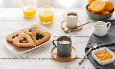 Breakfast concept with coffee, orange juice and cookies in heart shape with jam and chocolate