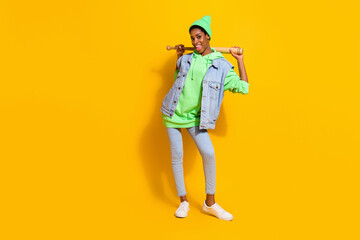Full length body size view of attractive cheerful girl holding bat posing isolated over bright yellow color background
