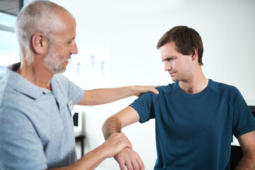 Thats exactly where the pain is. Cropped shot of a handsome mature male physiotherapist treating a...