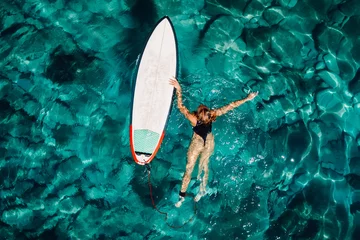 Fototapeten Surf woman float with surfboard in turquoise ocean. Aerial view © artifirsov