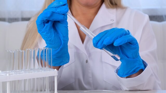 professional scientist takes a sample for a medical experiment. A research chemist works in a laboratory with a micropipette and a microscope