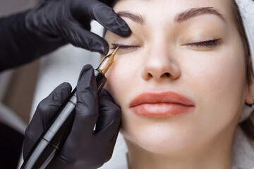Close-up of a woman, in a beauty salon with her eyes closed, a cosmetologist makes permanent...