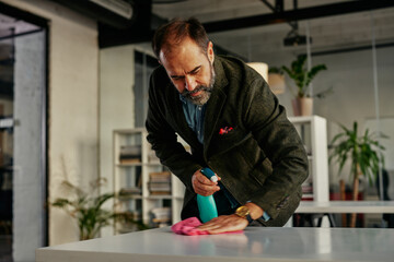 Obraz premium Businessman disinfecting desk at office