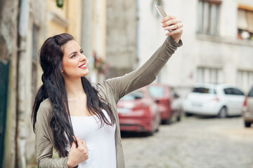 Young cute female using smartphone on the street.