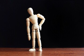 Wooden doll with lower back pain. Copy space for text. Black background.