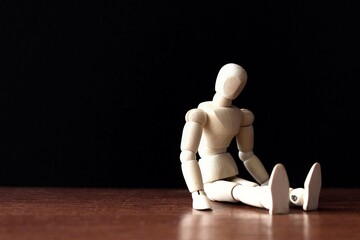 Wooden doll sit alone in the dark with copy space for text. Emotional, sad, frustrated concept.