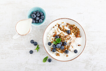 Bowl of granola with fresh blueberry, cottage cheese or curd, yogurt and nuts. Healthy food. Breakfast. Top view