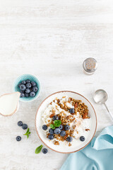 Bowl of granola with fresh blueberry, cottage cheese or curd, yogurt and nuts. Healthy food. Breakfast. Top view