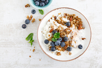 Bowl of granola with fresh blueberry, cottage cheese or curd, yogurt and nuts. Healthy food. Breakfast. Top view