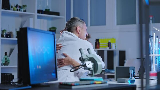 Happy team of scientists celebrating achievement, hugging and giving high five