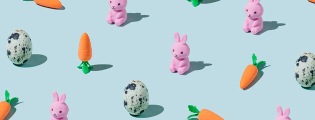 Banner made Easter pattern made with eggs, easter bunny, carrots on blue background. Creative minimal holiday concept. Flat lay, top view