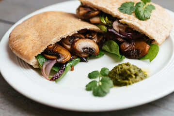 Pita breads filled with sauteed mushrooms and onions with winter purslane and corn salad, served with zhoug