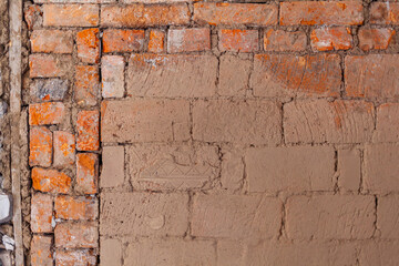 Repair of an old brick wall of a home stove. Different red bricks are laid in the wall after repair. Brick background