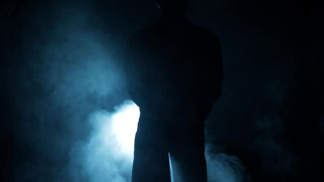 Cinematic shot of a man in long coat with axe in his hand, in fog and cinematic light. High quality Footage.