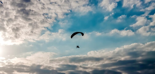 Paraglider on the background of a sunset sky with clouds in summer