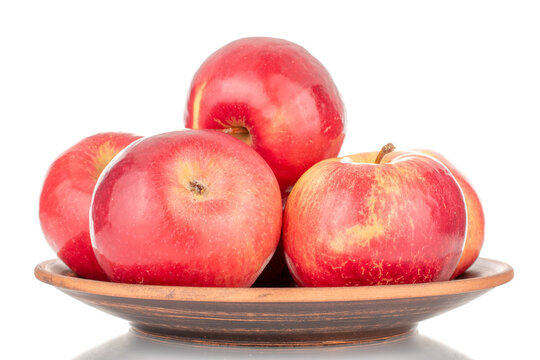 Several juicy, ripe, red apples on a plate of clay, macro, isolated on a white background.
