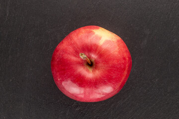 One juicy organic, red apple on slate rock, macro, top view.

